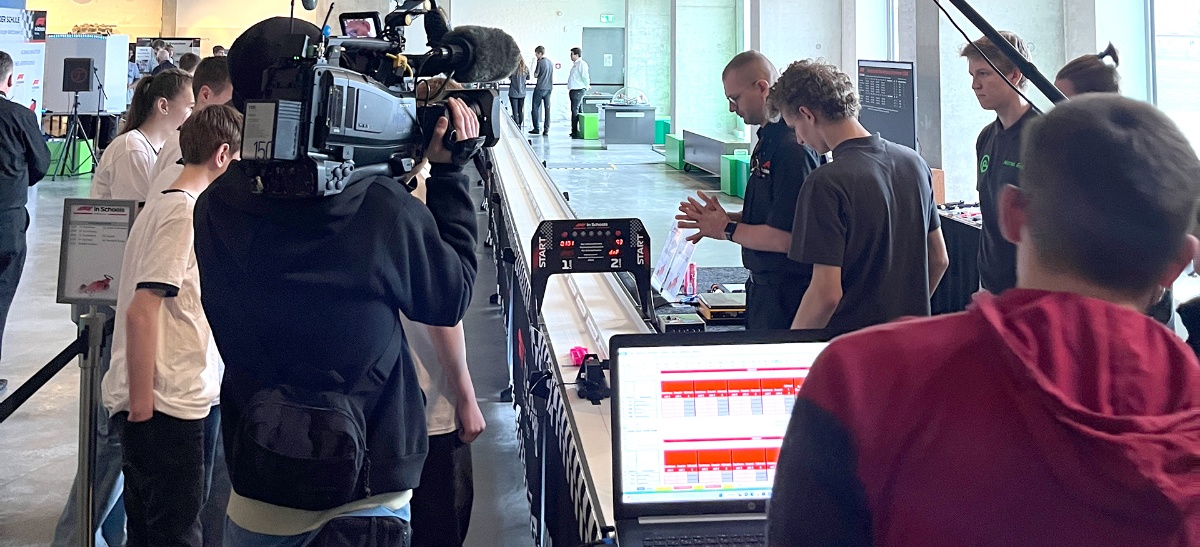 Teammitglieder und Reporter stehen zum Rennstart an der F1 für Schulen Bahn